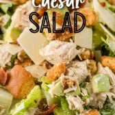 Close up shot of caesar salad with chicken and bacon in a bowl with recipe title on top of image