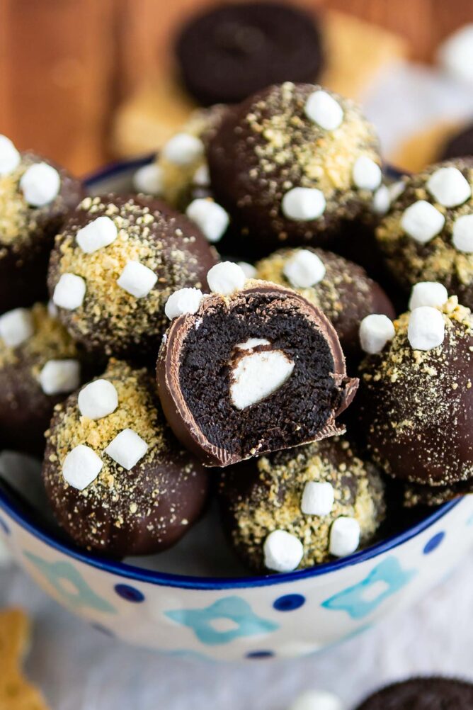 Bowl full of S'more oreo truffles with one cut in half to show mini marshmallow in the middle
