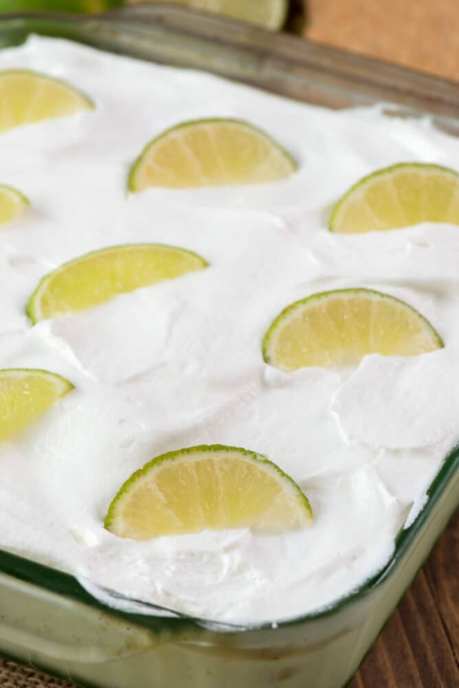 Key lime eclair dessert in glass baking dish with lime wedges on top