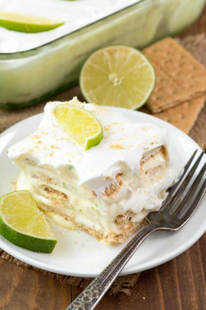 One slice of key lime eclair on a plate topped with lime wedges