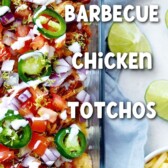 Close up overhead shot of bbq chicken totchos next to shredded cheese and lime wedges with recipe title in middle of photo