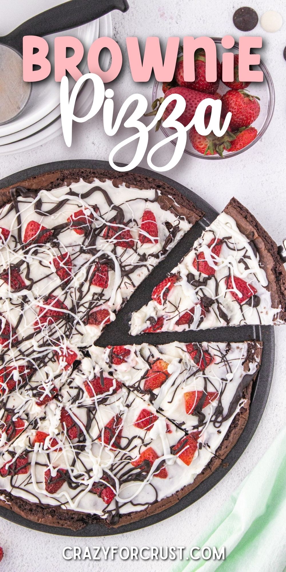 Overhead shot of brownie pizza with one slice being pulled away from the full pizza with recipe title on top of image