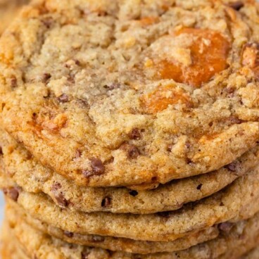 Overhead shot of a large stack of butterfinger cookies with recipe title on top of image