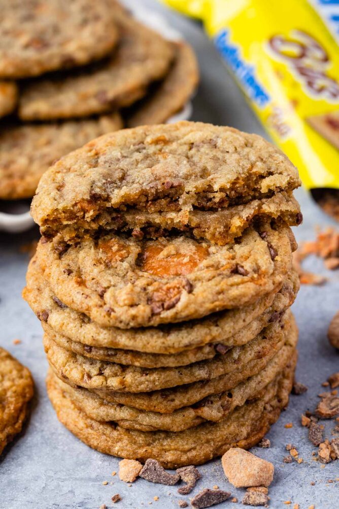 Large stack of butterfinger cookies with top cookie cut in half to show inside butterfinger bits