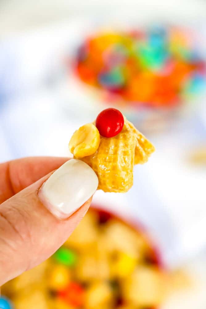 Hand holding one cluster of caramel chex mix close to camera lense