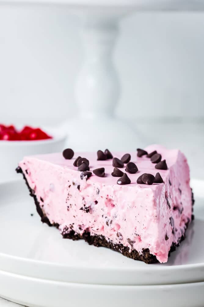 One slice of cherry jello pie on a plate topped with chocolate chips