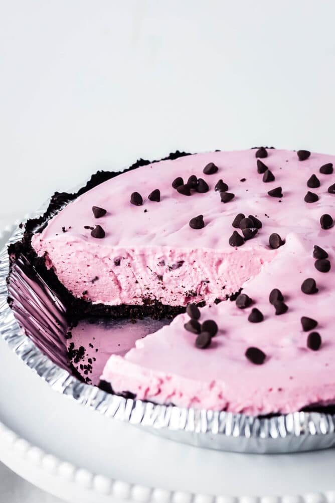 Cherry jello pie topped with chocolate chips with one slice missing from pie dish
