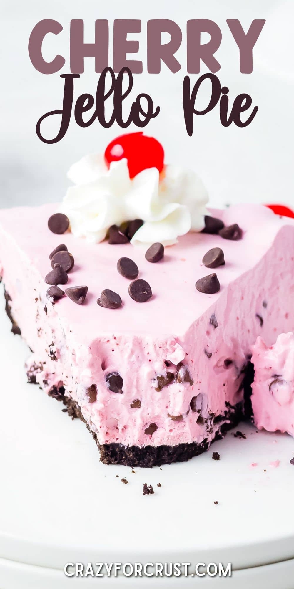 One large slice of cherry jello pie topped with chocolate chips, whipped cream and cherry with first bite missing and recipe title on top of image