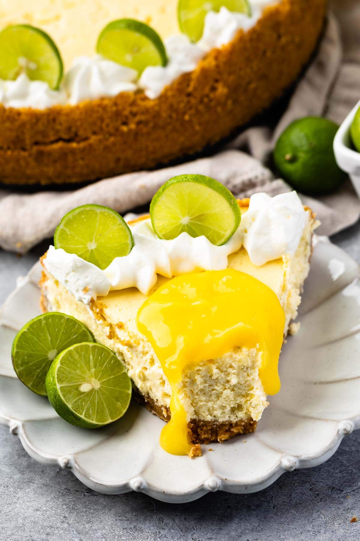 slice of cheesecake on white plate with lime curd on top and bite missing