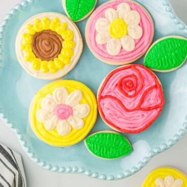 Overhead shot of all decorated sugar cookies on a plate with recipe title on top of image