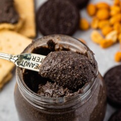 Small spoon scooping out oreo peanut butter from small mason jar