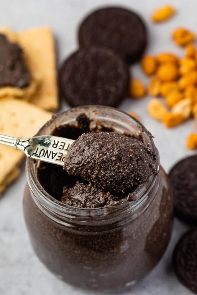 Small spoon scooping out oreo peanut butter from small mason jar