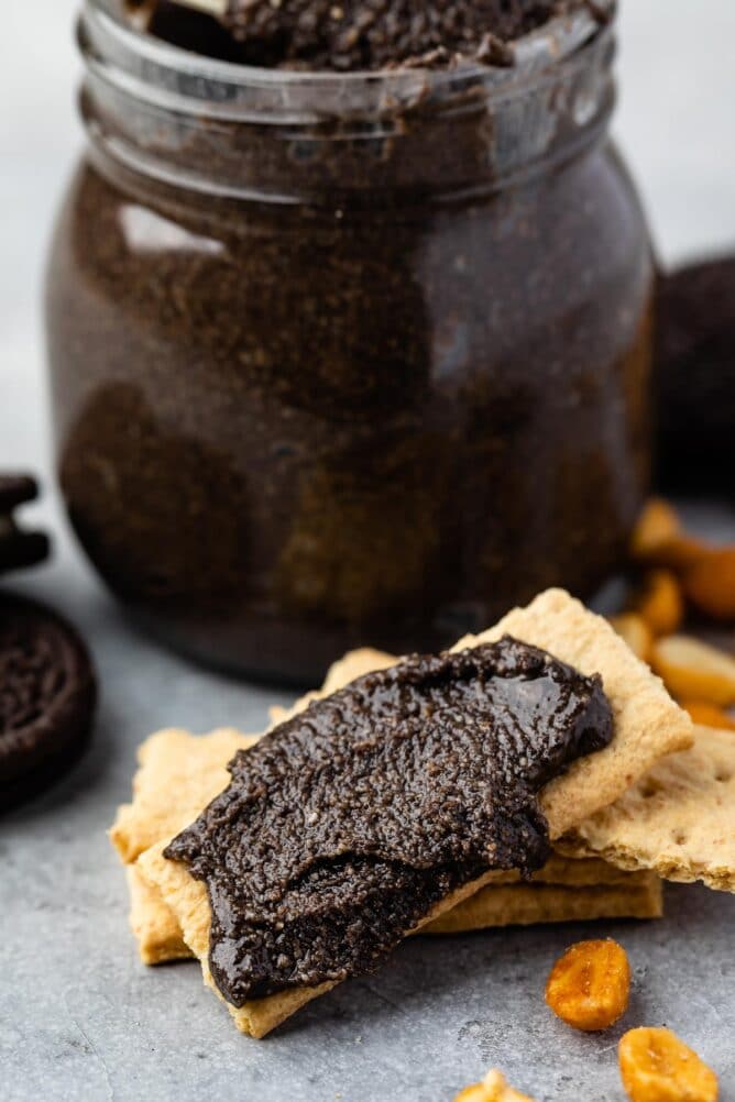 Oreo peanut butter spread onto a graham cracker with jar in background