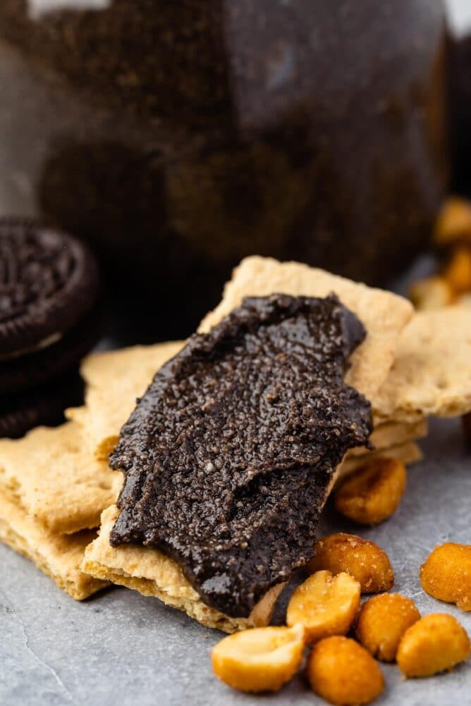 Oreo peanut butter spread onto a graham cracker with jar in background