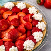 Close up shot of no bake strawberry shortcake pie topped with whipped cream dollops