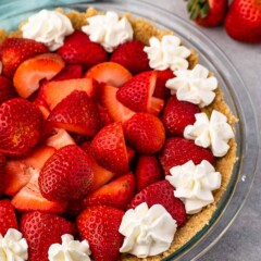 Close up shot of no bake strawberry shortcake pie topped with whipped cream dollops