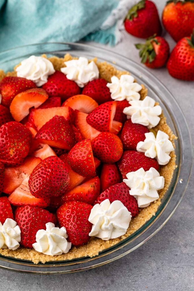 Close up shot of no bake strawberry shortcake pie topped with whipped cream dollops