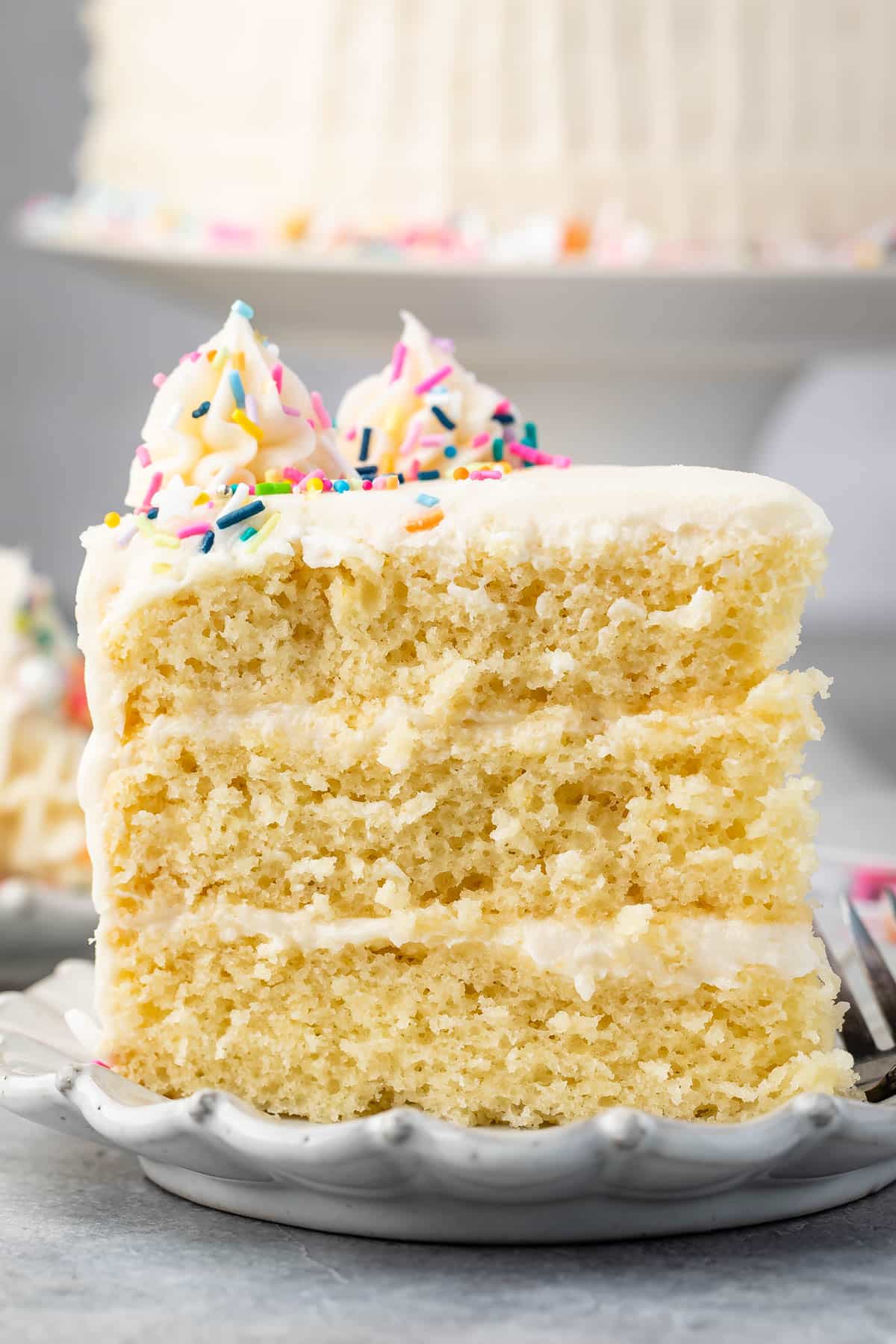 slice of 3 layer yellow cake on white plate.