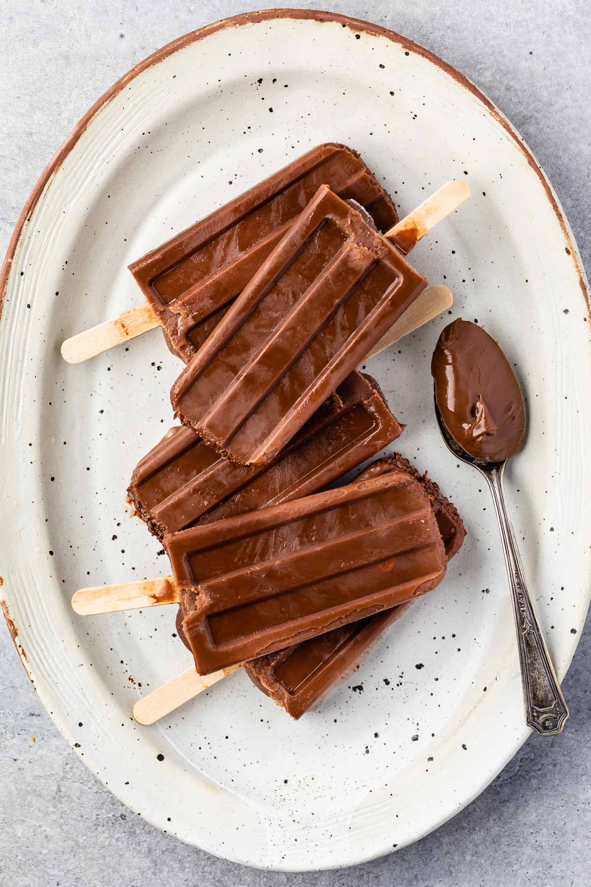 Overhead shot of 2 ingredient fudge pops on a serving platter next to a spoonful of nutella