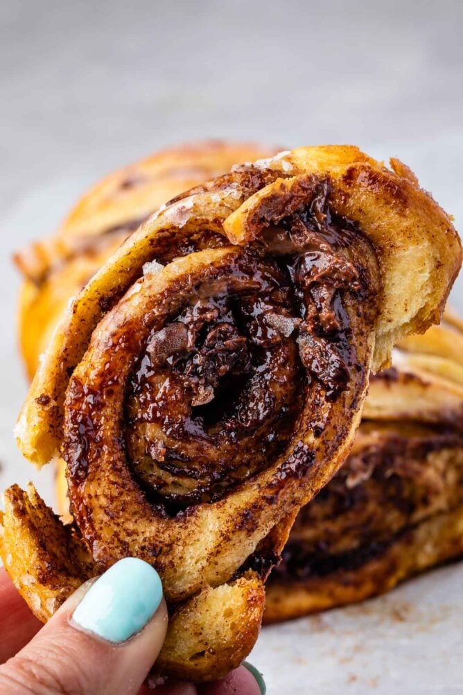 Hand holding up a piece of chocolate cinnamon roll pull apart bread close to the camera lens