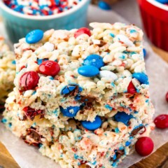 Two 4th of july rice krispie treats stacked on top of eachother with more sprinkles and M&Ms in background