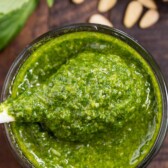 Overhead shot of easy basil pesto in a small glass dish with spoon coming out