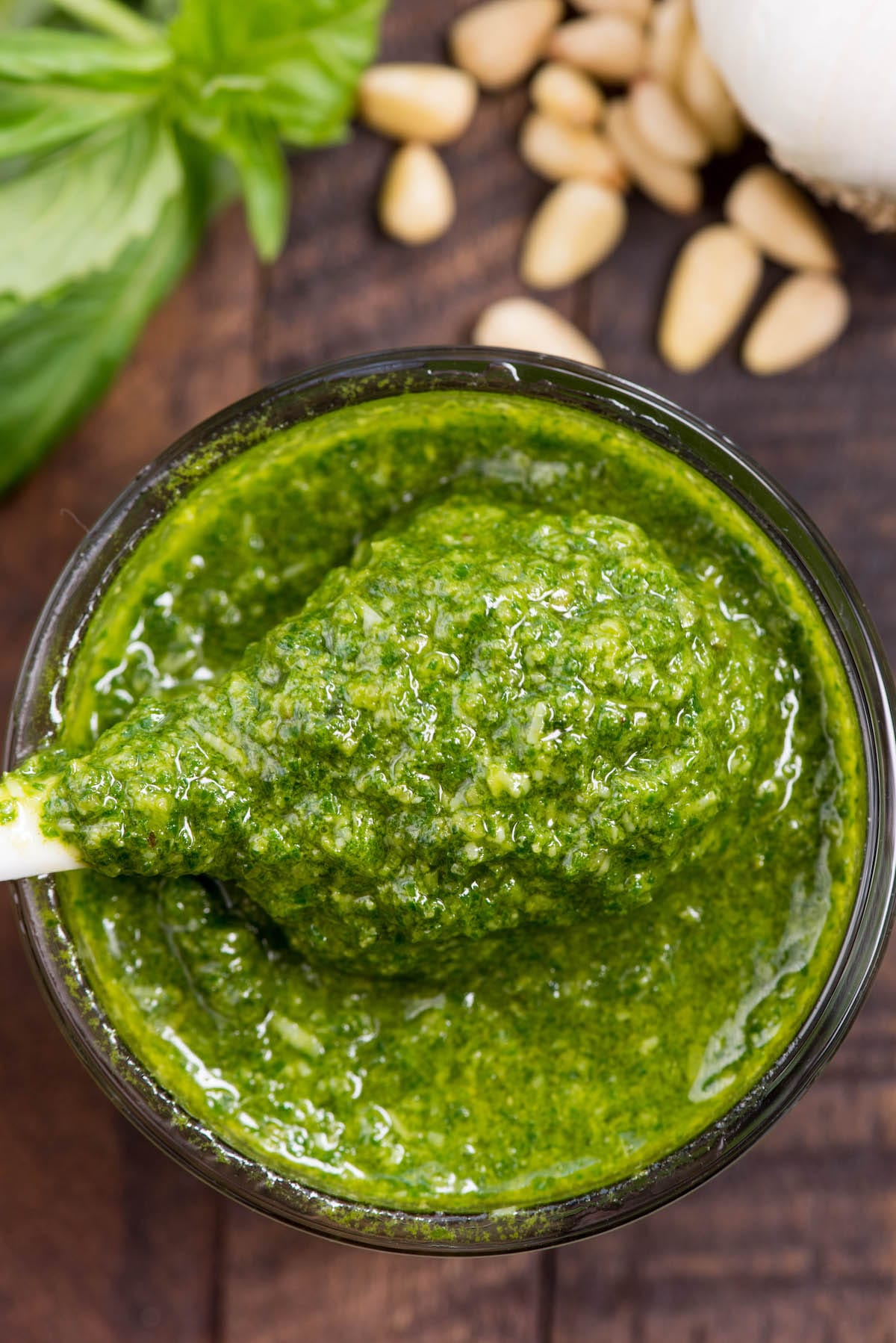 Overhead shot of easy basil pesto in a small glass dish with spoon coming out