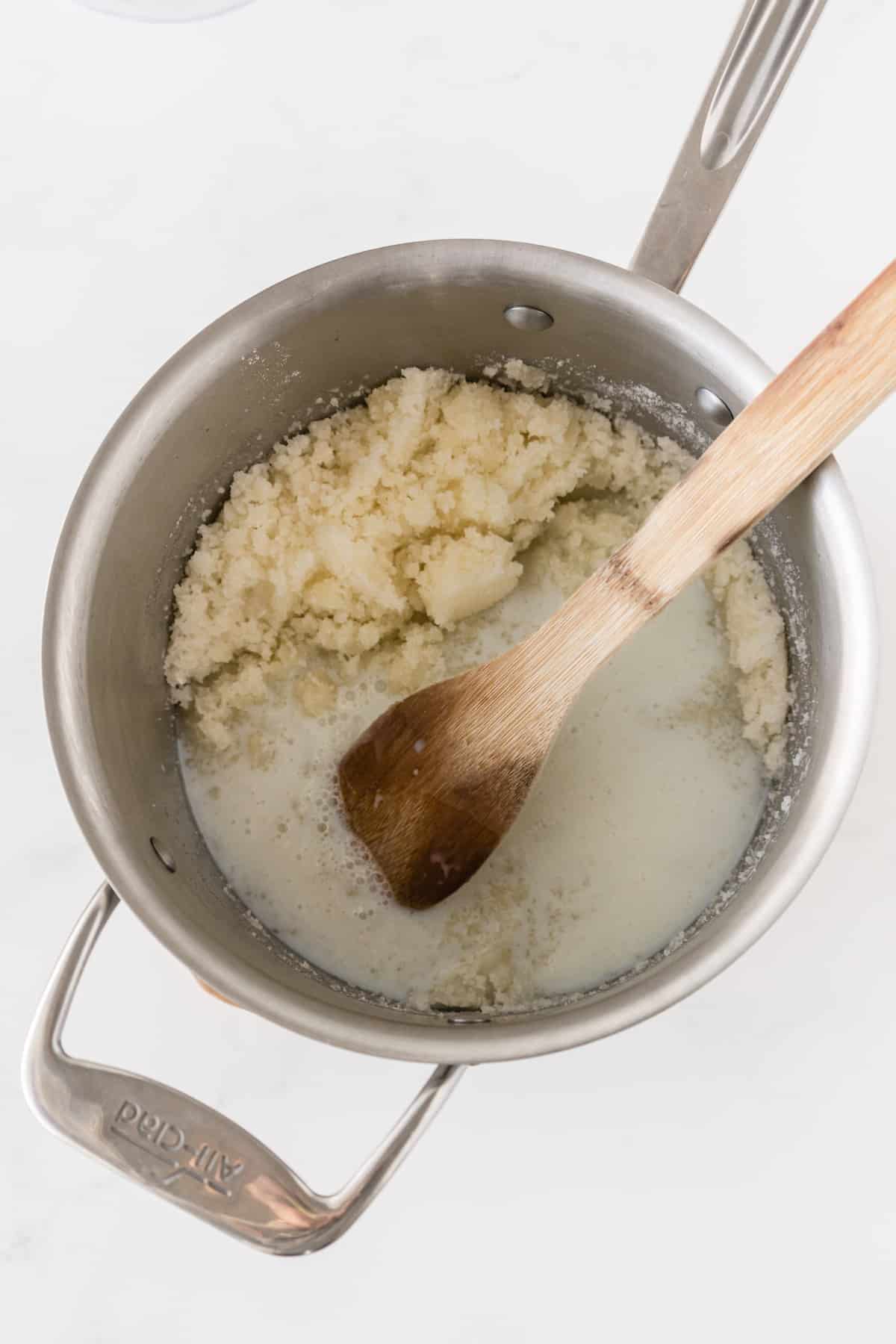 butter sugar mixture in saucepan with milk and wooden spoon