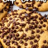 Close up overhead shot of ultimate stuffed peanut butter cookies on parchment paper surrounded by mini chocolate chips with recipe title on top of image