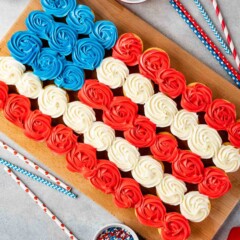 Overhead shot of american flag cupcake cake next to patriotic toppings and straws