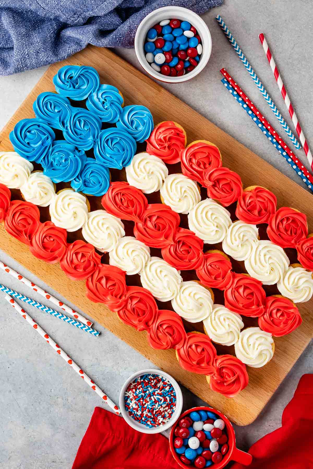 Overhead shot of american flag cupcake cake next to patriotic toppings and straws