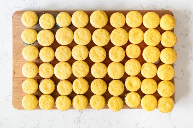 Overhead shot of vanilla cupcakes lined up on cutting board before being decorated