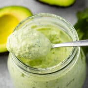 Overhead shot of avocado cilantro crema in a small mason jar with spoon coming out of jar