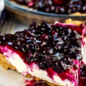 One slice of blueberry cream cheese pie on a plate with rest of pie behind it and recipe title on top of image