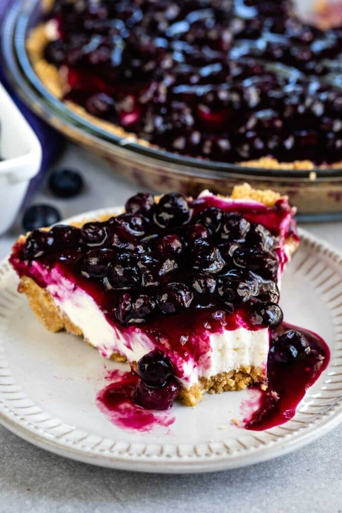 One slice of blueberry cream cheese pie on a plate with a bite missing