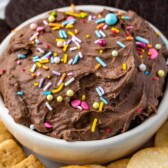 Cake batter dip in a bowl topped with sprinkles and surrounded by dippers with recipe title on top of image