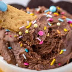 Graham cracker being dipped into a bowl of cake batter dip