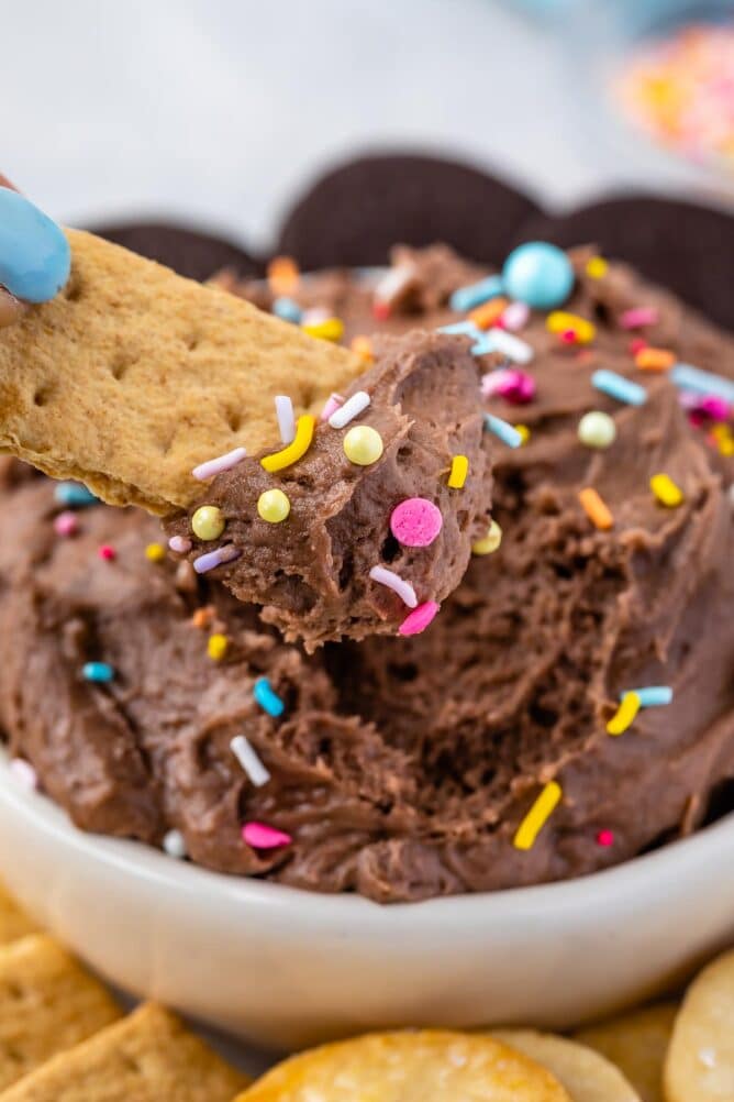 Graham cracker being dipped into a bowl of cake batter dip