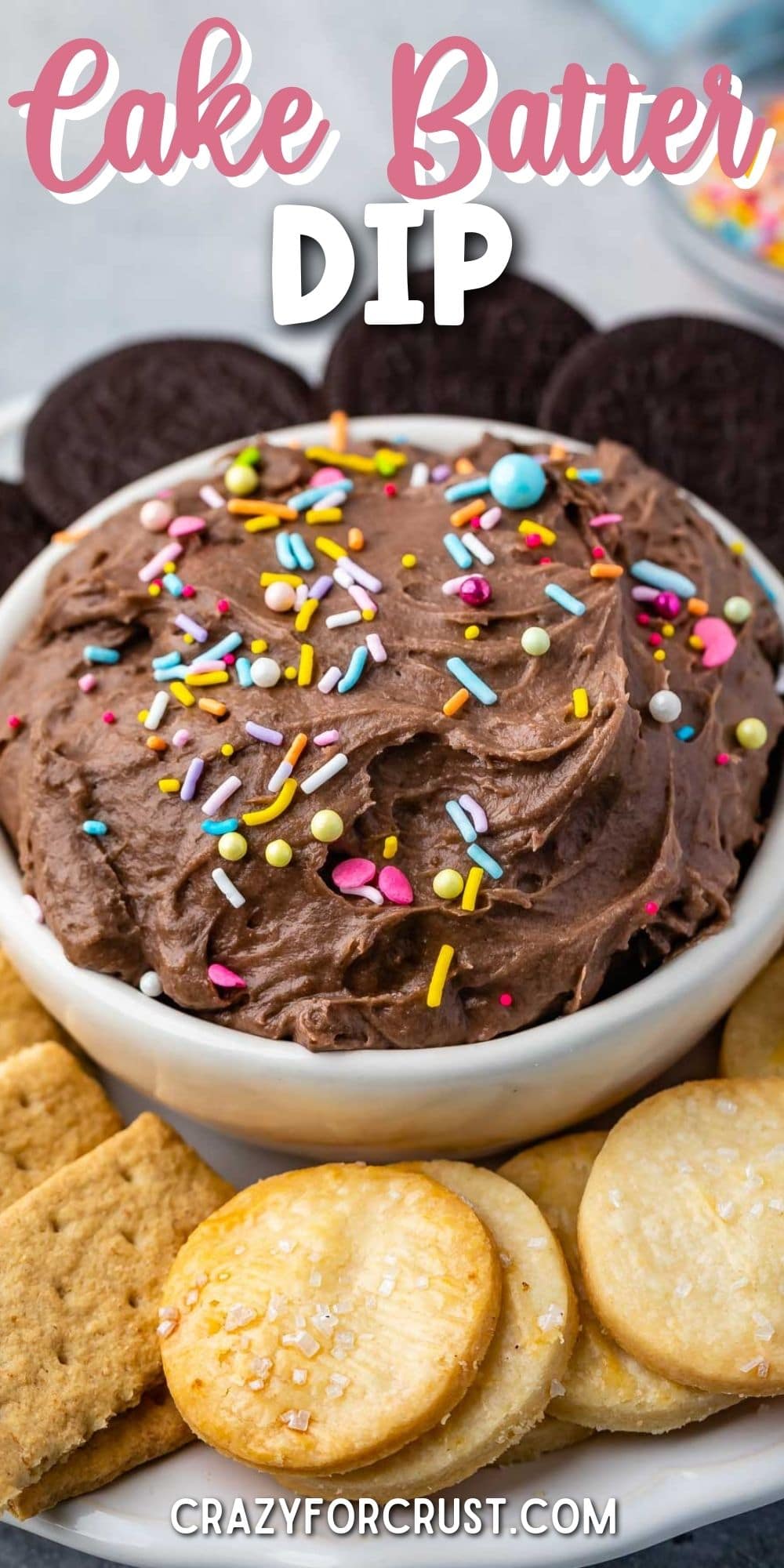 Cake batter dip in a bowl topped with sprinkles and surrounded by dippers with recipe title on top of image