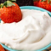 Close up shot of cheesecake dip with a strawberry in it and recipe title on top of image