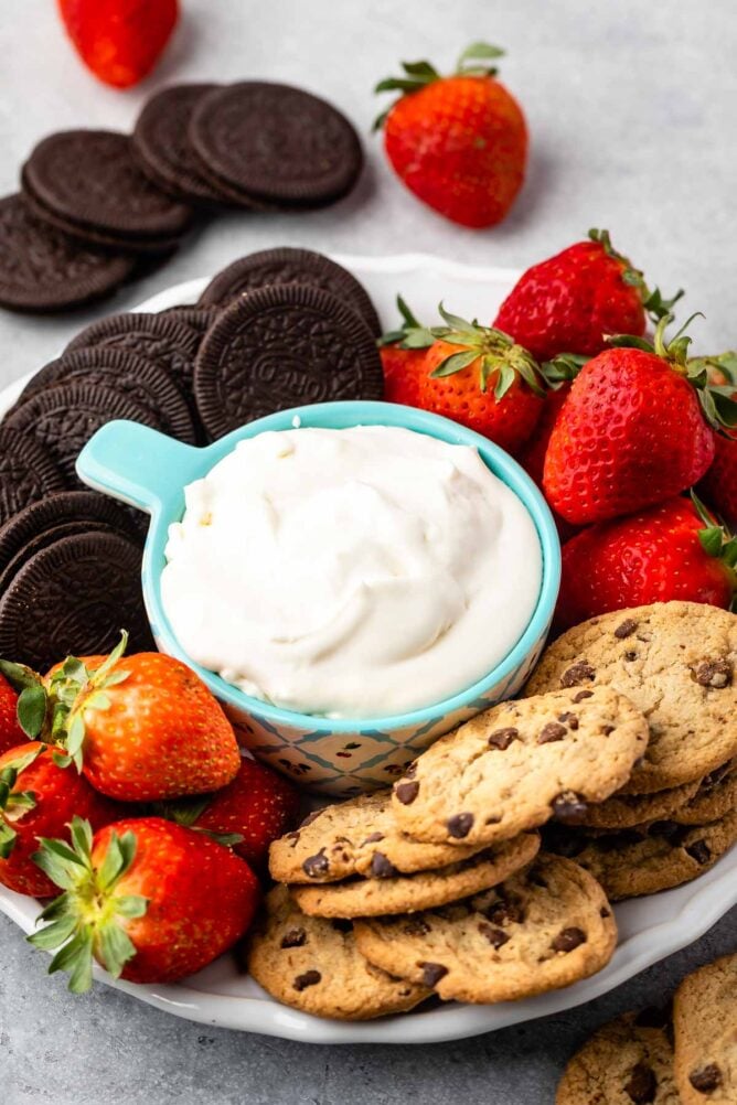 Cheesecake dip on a platter surrounded by cookies and strawberries