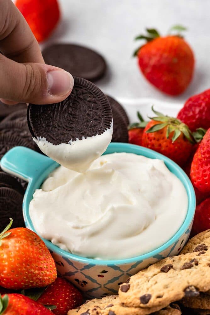 Oreo being dipped into cheesecake dip