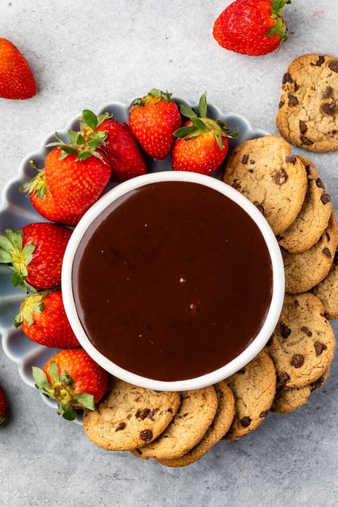Overhead shot of chocolate dip surrounded by chocolate chip cookies and strawberries