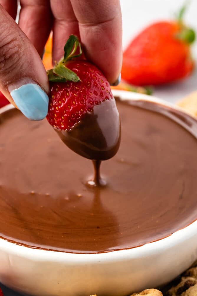 Strawberry being dipped into chocolate dip