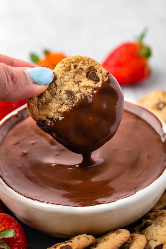 Chocolate chip cookie being dipped into chocolate dip