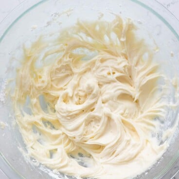 Overhead shot of cream cheese frosting in glass mixing bowl