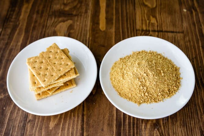two white plates with graham crackers and crumbs.