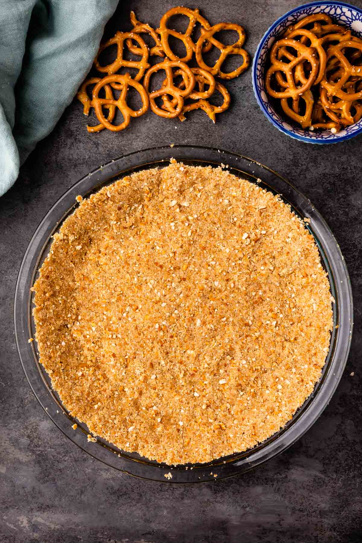 Overhead shot of pretzel crust in a glass pie dish next to pretzels