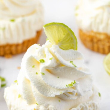 One mini no bake key lime cheesecake topped with a lime wedge and recipe title on top of image