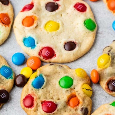 2 Ingredient M&m Cookies on parchment paper surrounded by more M&Ms with recipe title on top of image